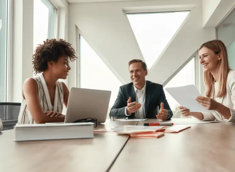 3 people smiling and working at a desk on their skills during training